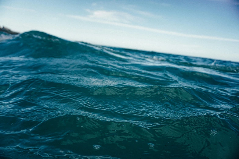 a man riding a surfboard on top of a wave in the ocean, a picture, unsplash, deep blue sea color, deep sadness, water line surface, a photo of a lake on a sunny day