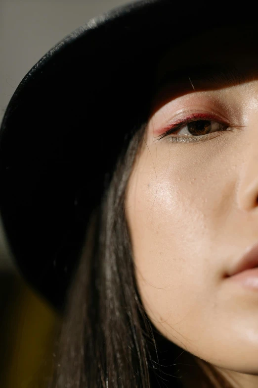 a close up of a person wearing a hat, an album cover, by Julia Pishtar, trending on pexels, hyperrealism, asian face, glossy skin, beauty mark on cheek, low angle shot