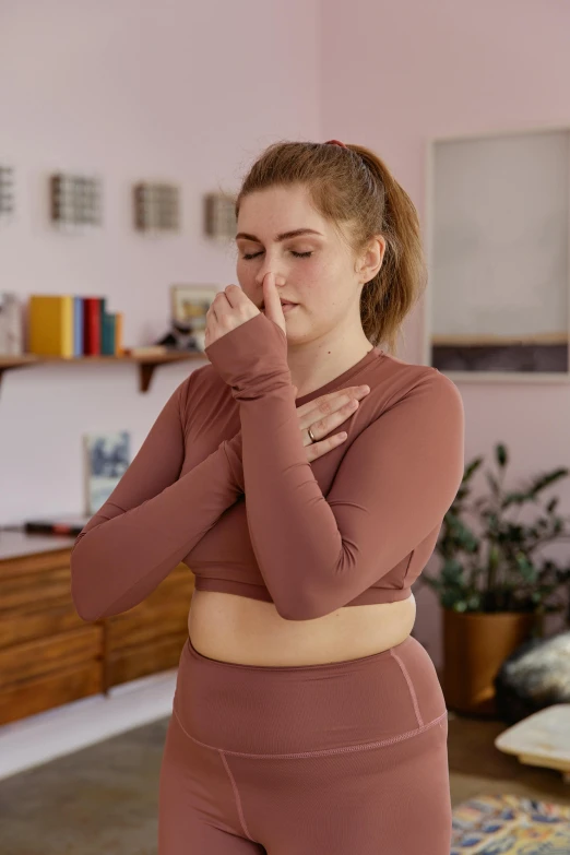 a young woman in a pink top is scratching her temple