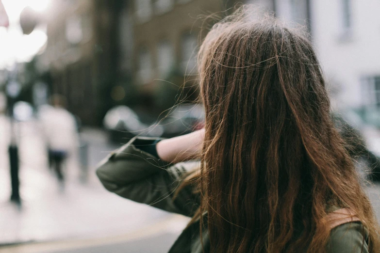 a woman with long brown hair walking down a street, trending on pexels, bedhead, teenage girl, over his shoulder, unblur