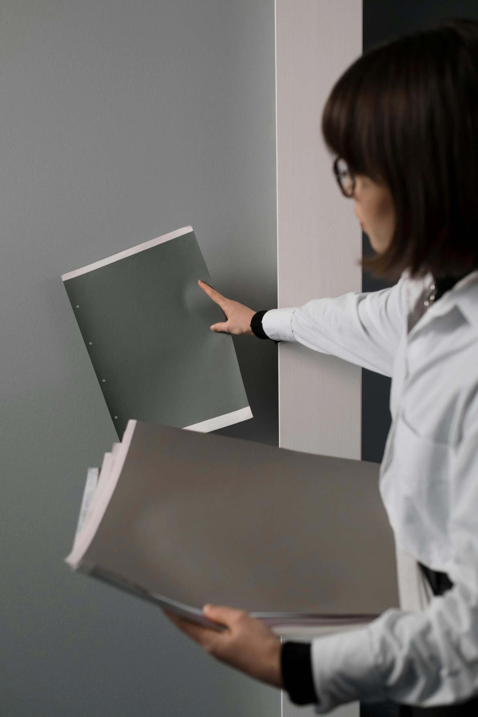 a woman in a white shirt holding a piece of paper, by jeonseok lee, unsplash, analytical art, metal panels, gray color, medical book, exiting from a wardrobe