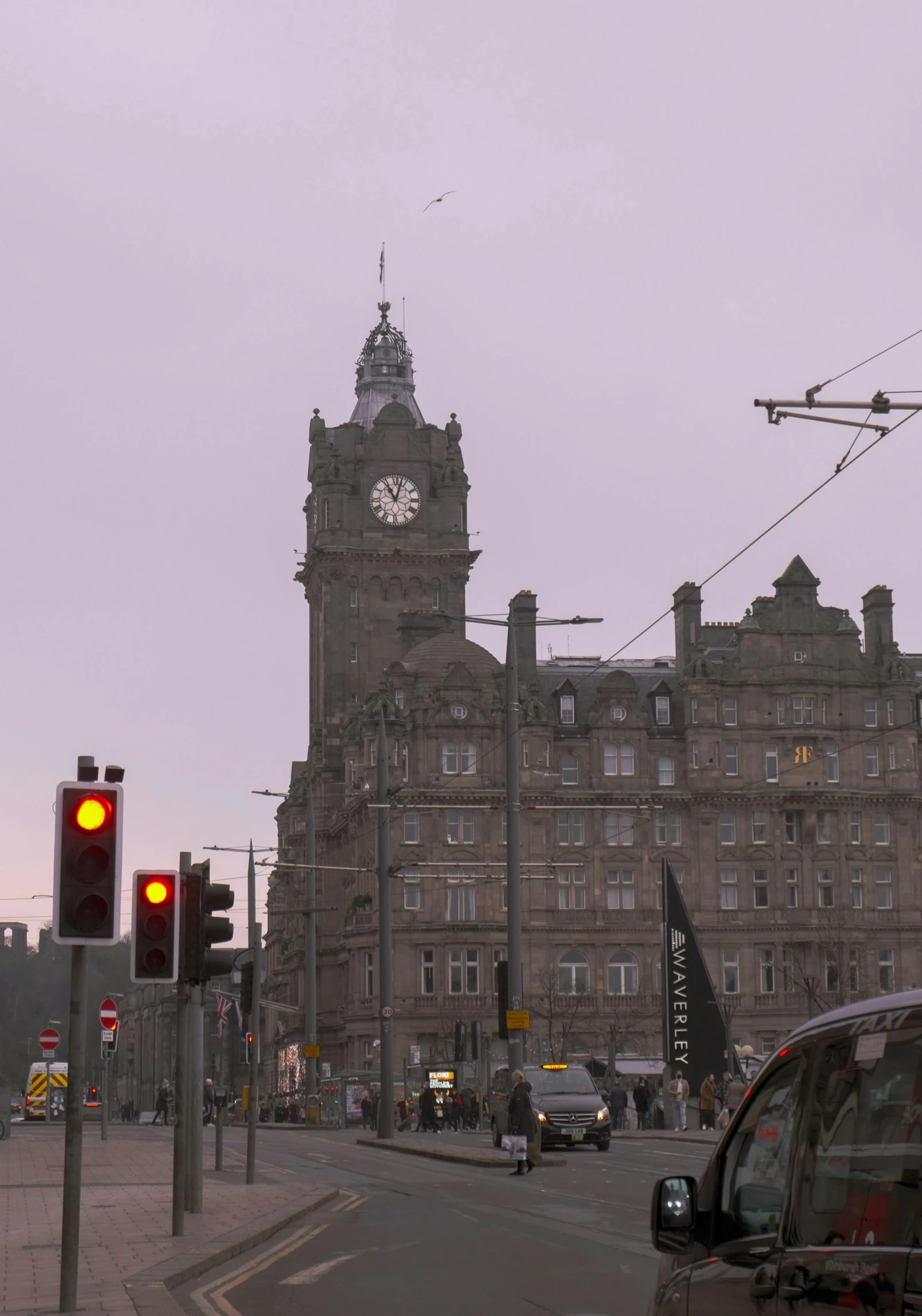 the traffic lights are red and yellow as the clock tower is visible