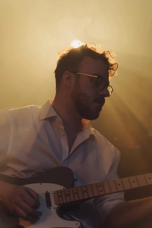 a man playing a guitar in front of the sun, an album cover, by Ryan Pancoast, wearing white suit and glasses, looking serious, casey baugh and james jean, profile portrait