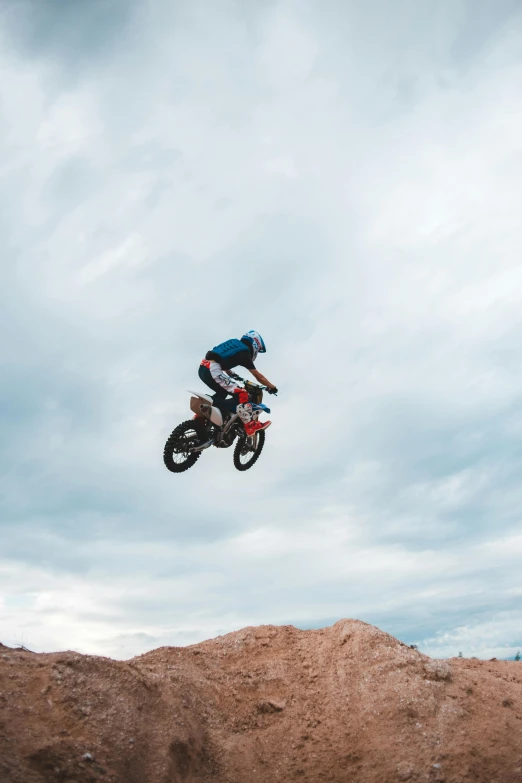 a man flying through the air while riding a dirt bike, unsplash, moab, ultra 4k, cloud jumper, hyper realistic