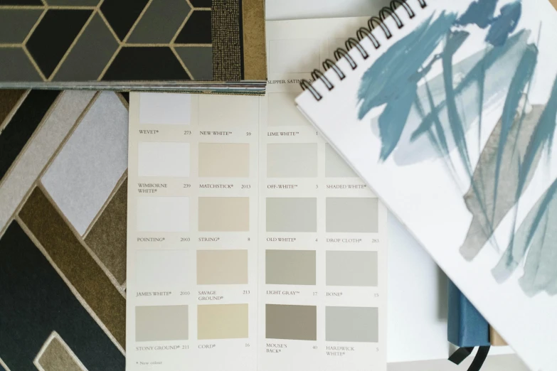 a book sitting on top of a table next to a notebook, a mosaic, inspired by Norah Neilson Gray, unsplash, color chart, beige color scheme, luxury materials, white paint