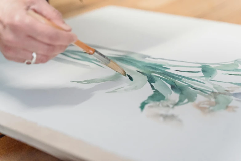 a person painting with a brush on a piece of paper, a watercolor painting, inspired by Hasegawa Tōhaku, trending on unsplash, jonathan yeo painting, on canvas, clean elegant painting, on a white table