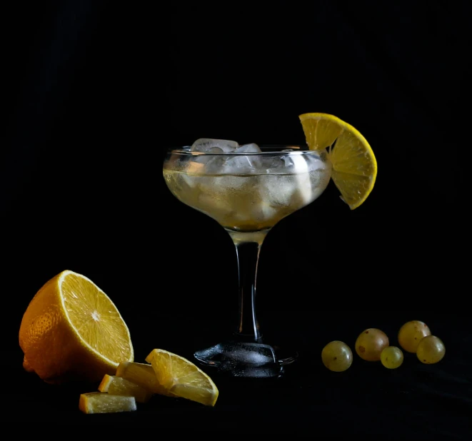 a close up of a drink in a glass on a table, a still life, by Ndoc Martini, pexels contest winner, lemons, translucent grapes, white moon and black background, battered