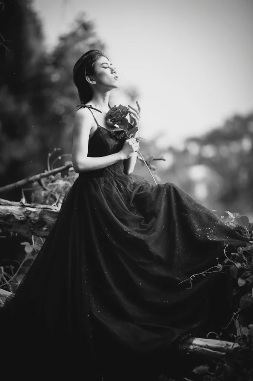 woman in a black dress holds flowers in one hand