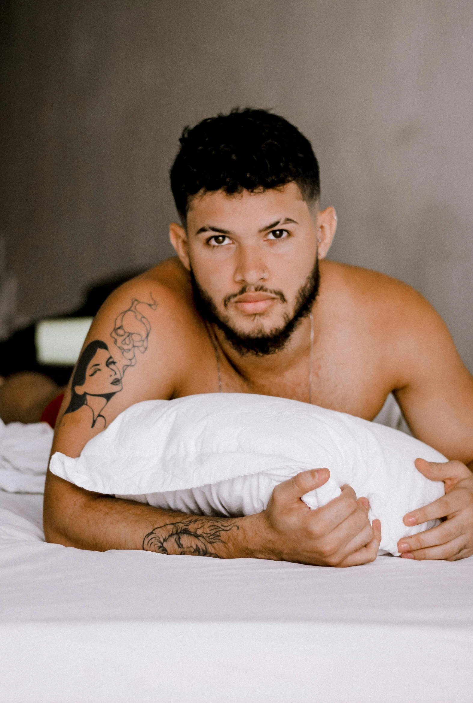 man with  laying on bed holding pillow