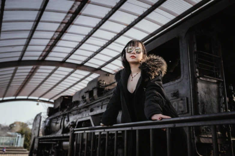 a woman is standing next to a train on rails