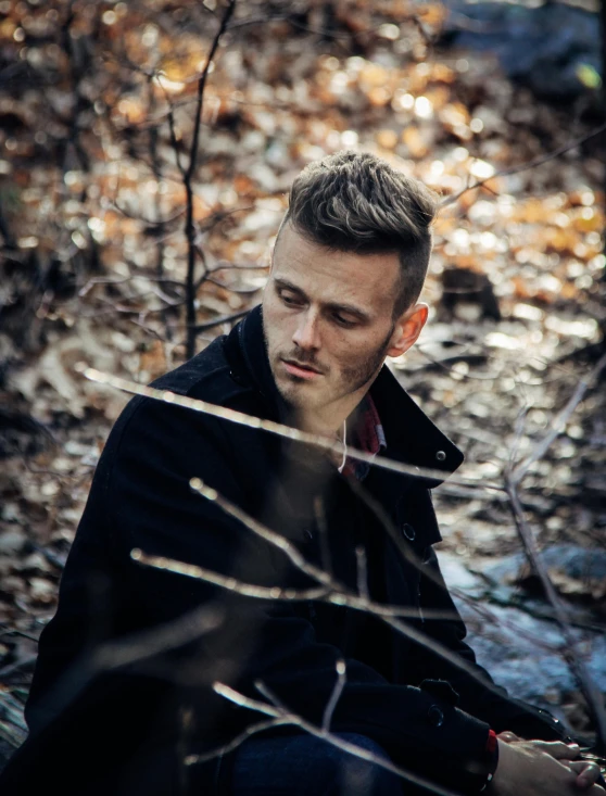 a man in the woods sitting down in the leaves