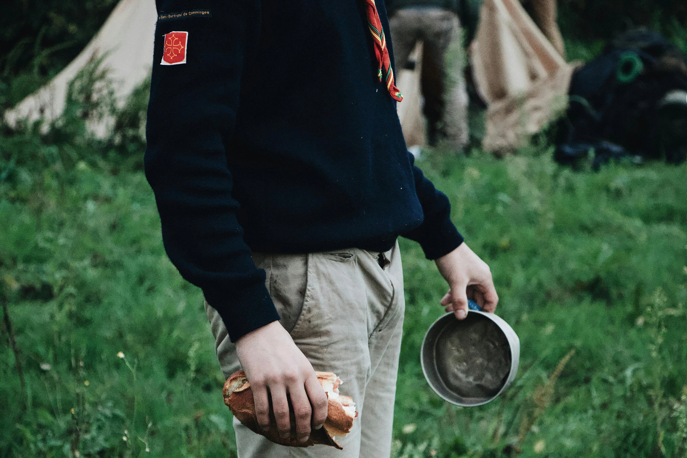 a man that is standing in the grass, holding a tin can, bread, wearing adventuring gear, scout boy