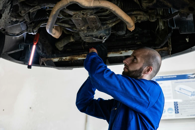 a man working on a car in a garage, a portrait, shutterstock, underbody, instagram photo, romanian, leaking