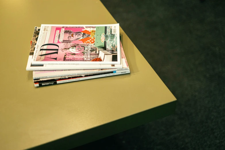 a stack of magazines sitting on top of a table, gold paint, lacquered oak reception desk, flat colour, thumbnail