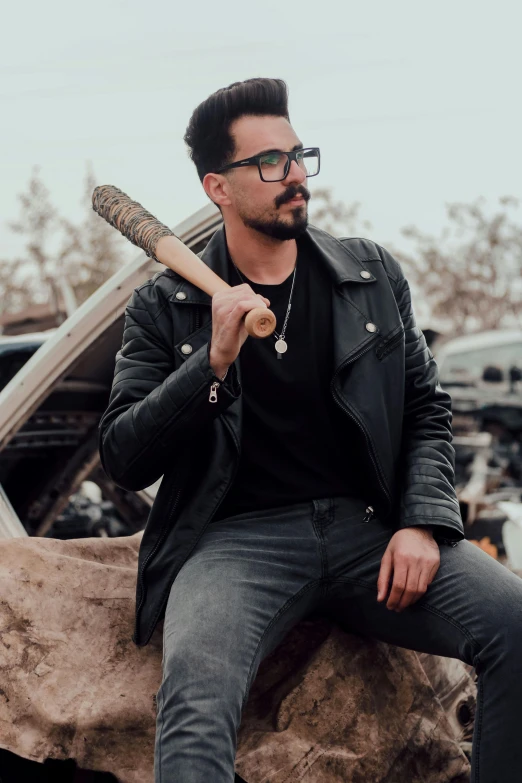 man with a baseball bat sitting on a rock