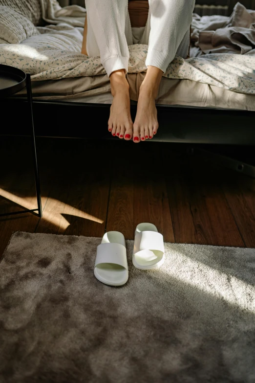 a woman sits on a bed with her feet propped up
