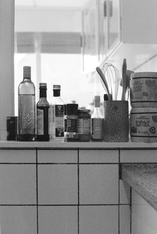 a black and white photo of a kitchen counter, inspired by Arnold Newman, flickr, bottles of spices, ✨🕌🌙, soviet apartment, booze