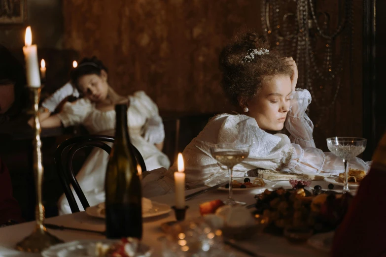 women sit at a table wearing dresses and tiara