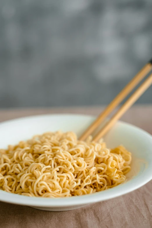 a bowl of noodles with chopsticks on a table, extra crisp image, square, polished : :, neck zoomed in