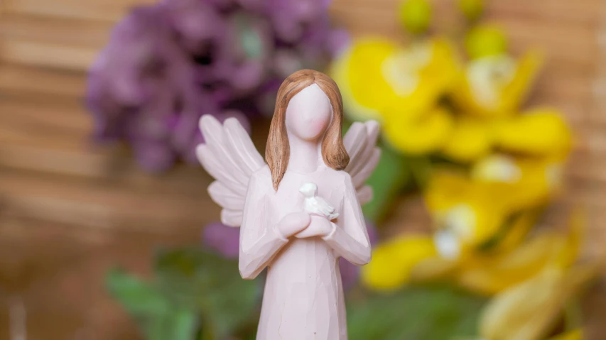 a close up of a figurine with flowers in the background, inspired by Marie Angel, pexels contest winner, heaven pink, hand carved brown resin, bird view, miniature product photo