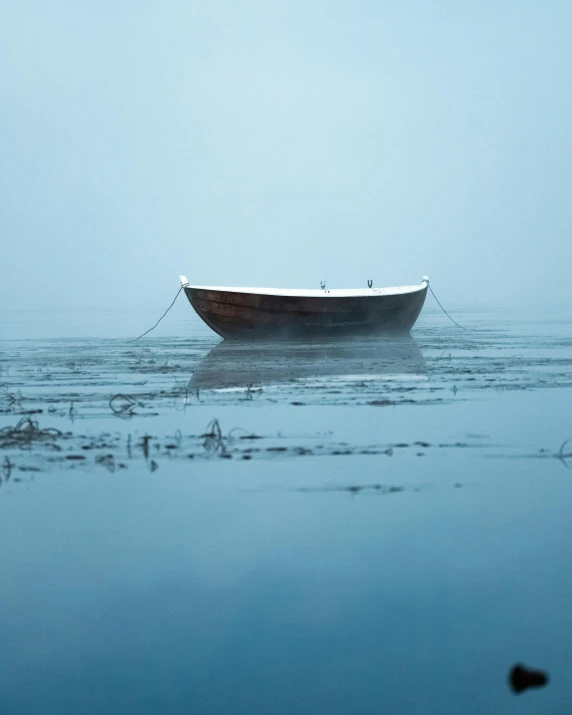 a boat floating on top of a body of water, unsplash contest winner, minimalism, pale blue fog, hammershøi, dark dingy, cute photo