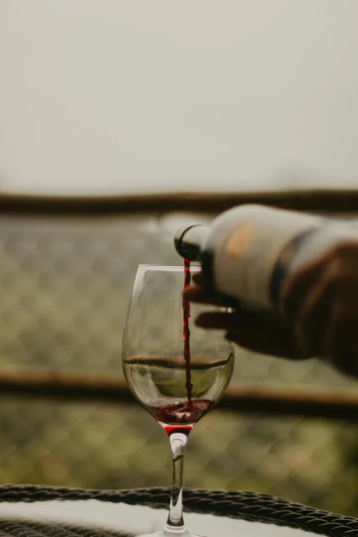 someone pouring red wine into a glass on top of a table