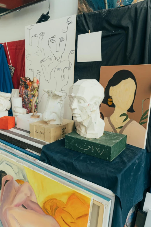 a table that has a bunch of art on it, a marble sculpture, model face, trends at art station, studio shot, art materials