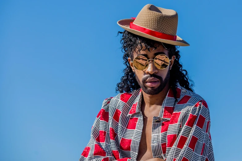 the man with long hair wears a hat and checkered shirt