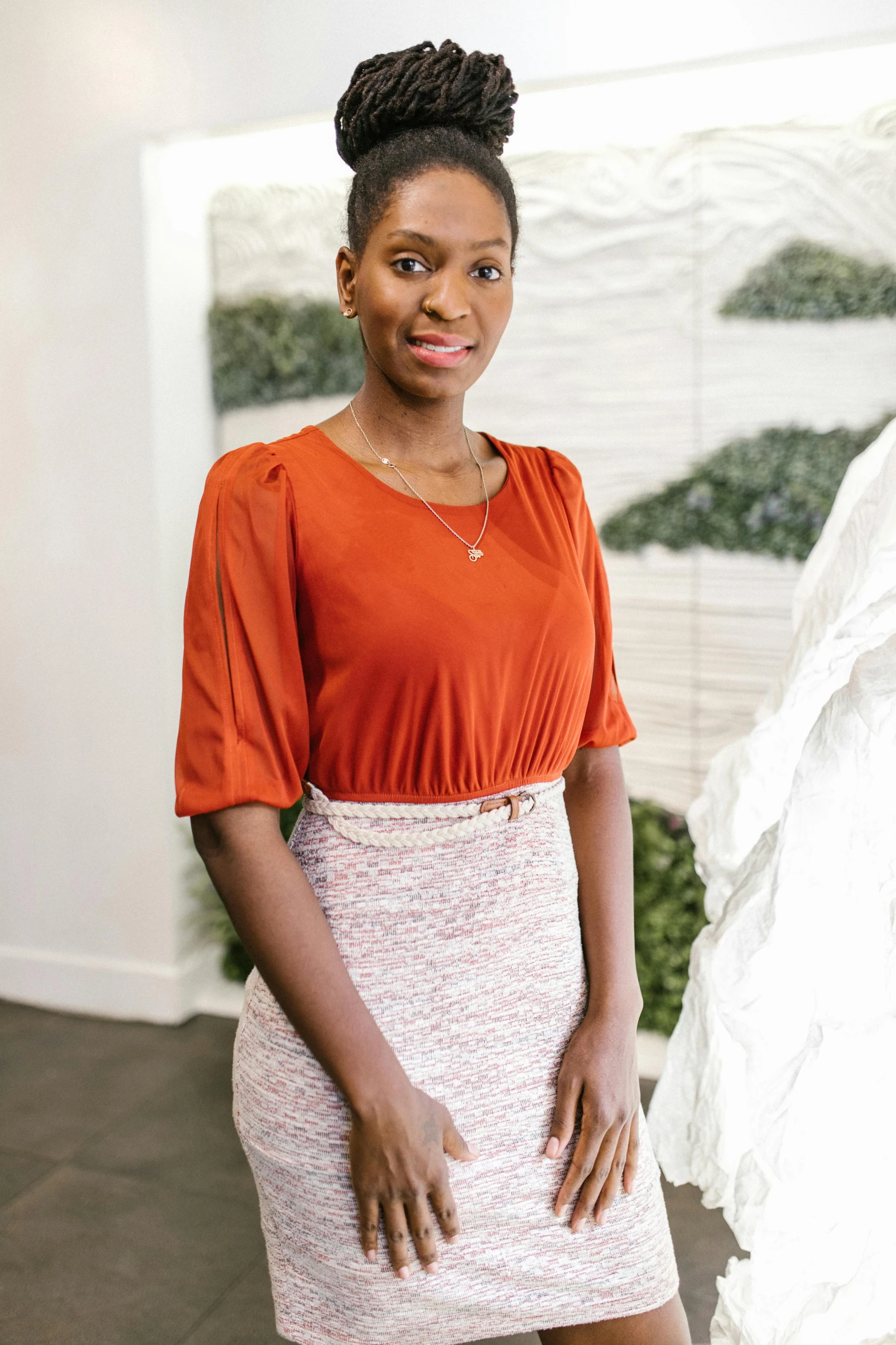 a woman standing in front of a sculpture, wearing business casual dress, maria borges, covered in coral, wearing white skirt