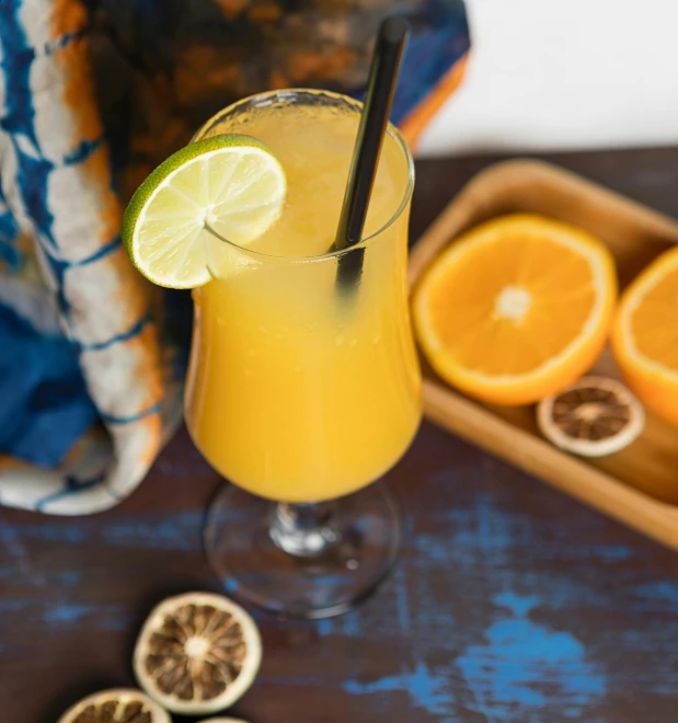 a glass of orange juice sitting on top of a table, neon yellow madhubani, thumbnail, natural sunlight, recipe