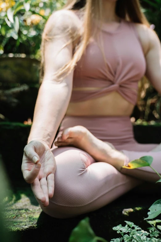 a woman sitting in a lotus position with her hands in the air, trending on pexels, big leaf bra, low detail, pink, gently caressing earth