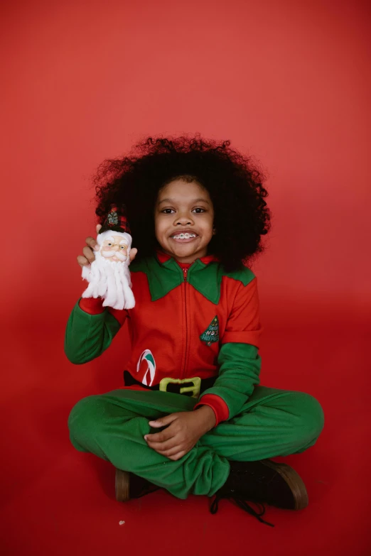 a girl sitting on the floor holding a christmas ornament