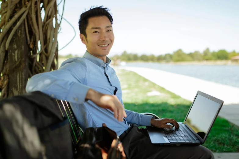 a man sitting on a bench with a laptop, by Simon Gaon, on a riverbank, darren quach, profile image