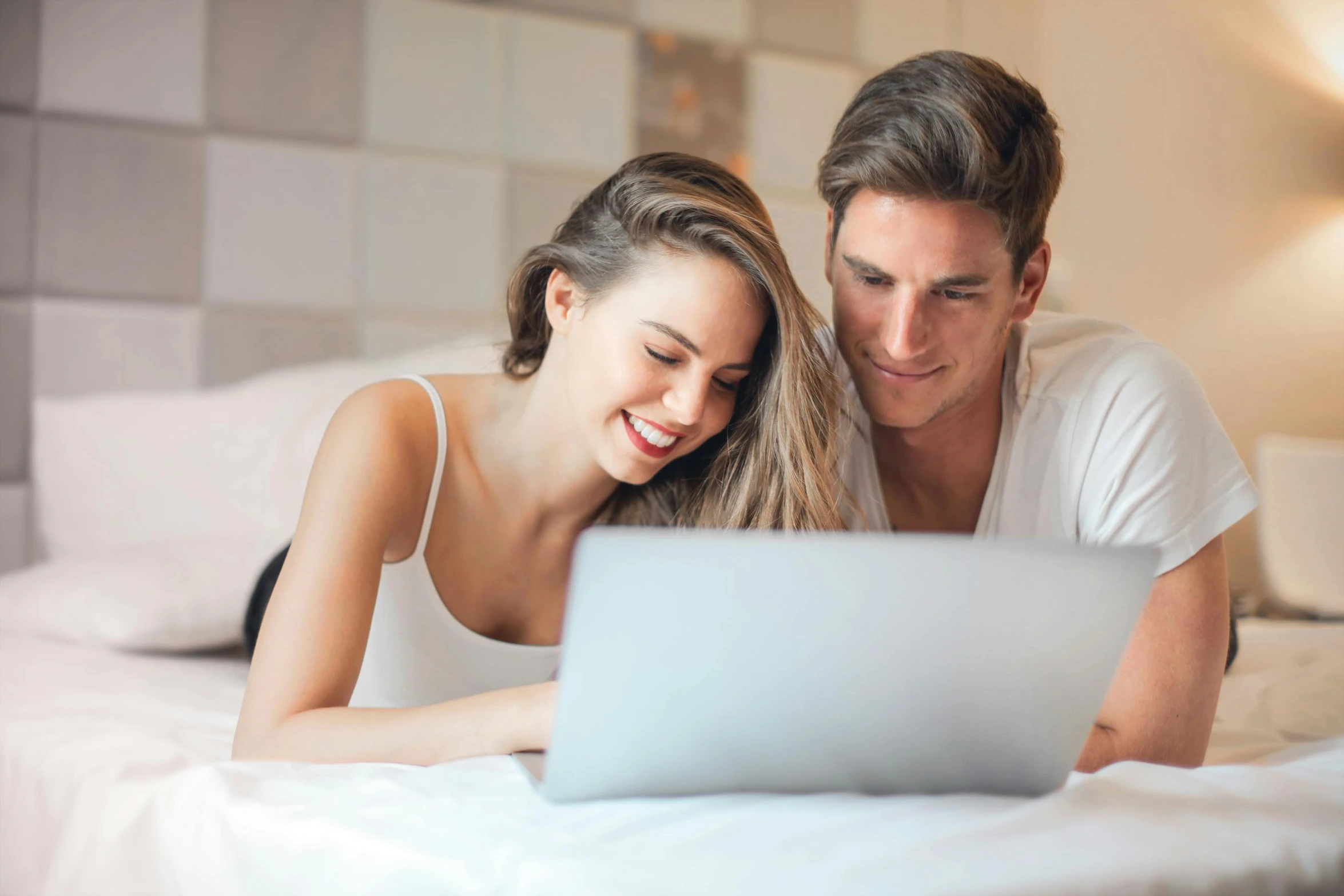 a man and woman laying on a bed looking at a laptop, a screenshot, pexels, 9 9 designs, caucasian, smiling couple, computer game