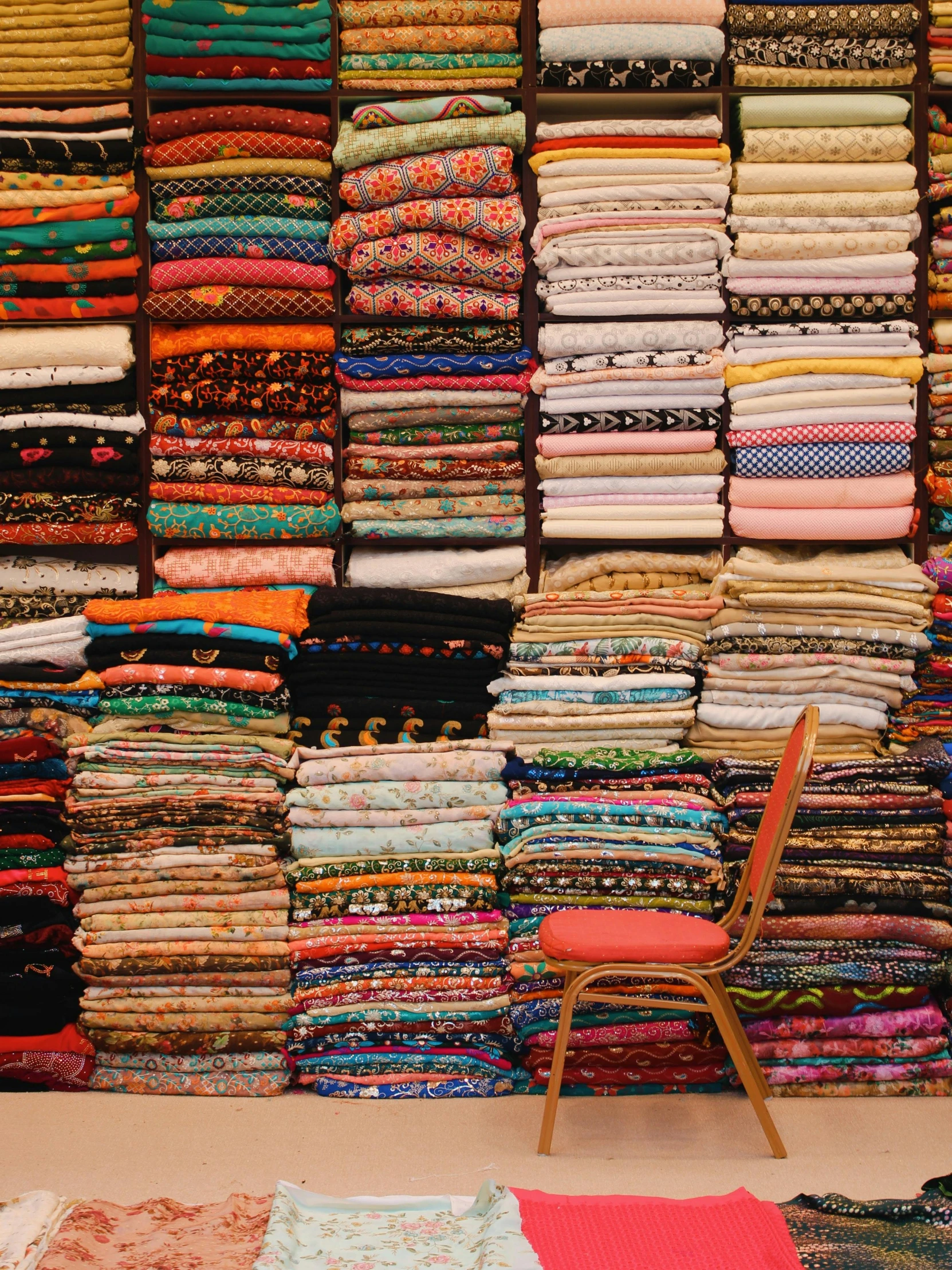 a room filled with lots of different colored fabrics, inspired by Andreas Gursky, trending on unsplash, middle eastern, stacked, facing away, sitting on a store shelf