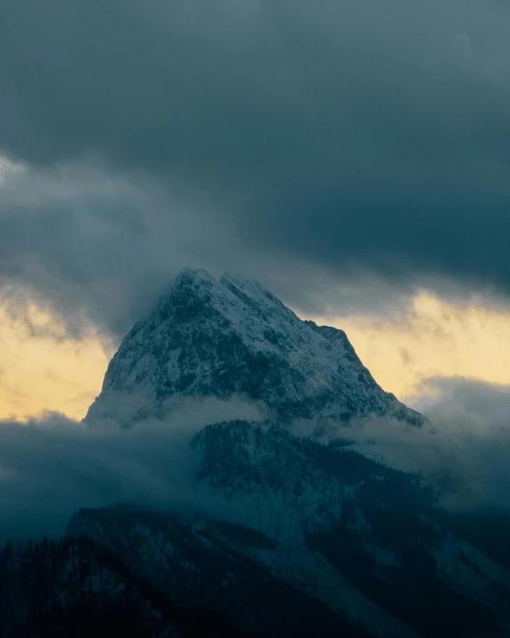 clouds move by behind a mountain in this image