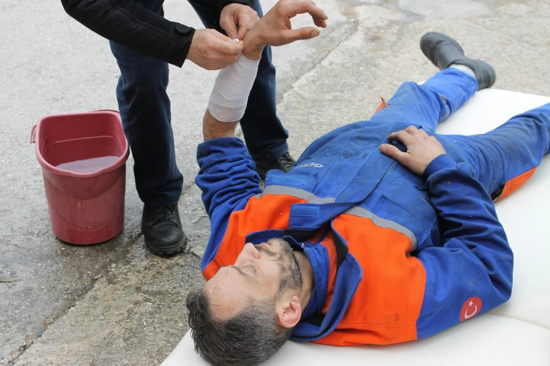 a man laying on the ground with a bandage, a photo, happening, safe for work, raising an arm, maintenance, derealisation
