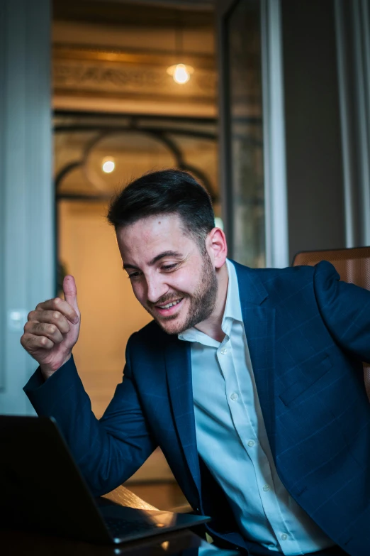 a man in a suit smiling at his laptop