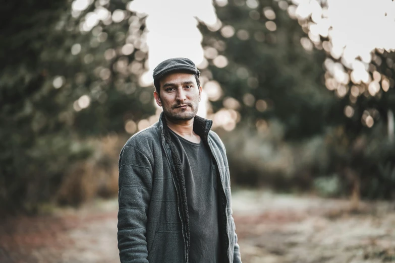 a man in a black jacket and hat in a field