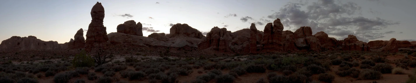 a group of rocks sitting in the middle of a desert, by Ryan Pancoast, unsplash, tonalism, panorama view, arches, late afternoon, taken in the late 2010s