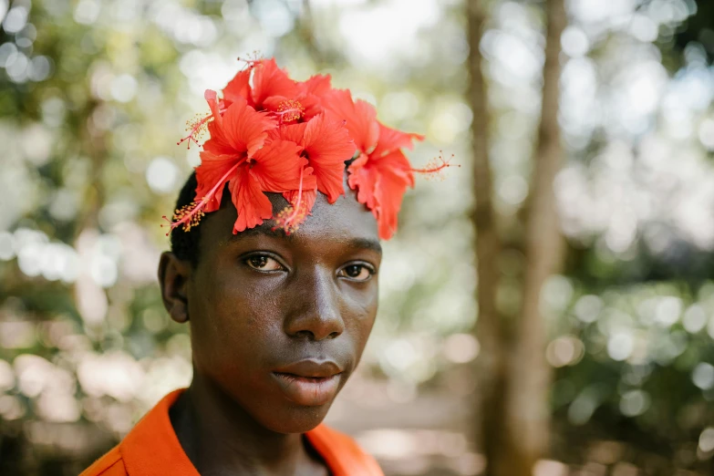 a young man with a red flower on his head, by Dietmar Damerau, pexels contest winner, afrofuturism, in the jungle. bloom, orange flowers, adut akech, wearing a laurel wreath