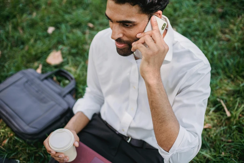 a man sitting in the grass talking on a cell phone