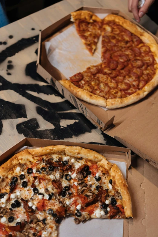 a couple of pizzas sitting on top of a table, black and brown colors, pizza box, top - down photograph, image