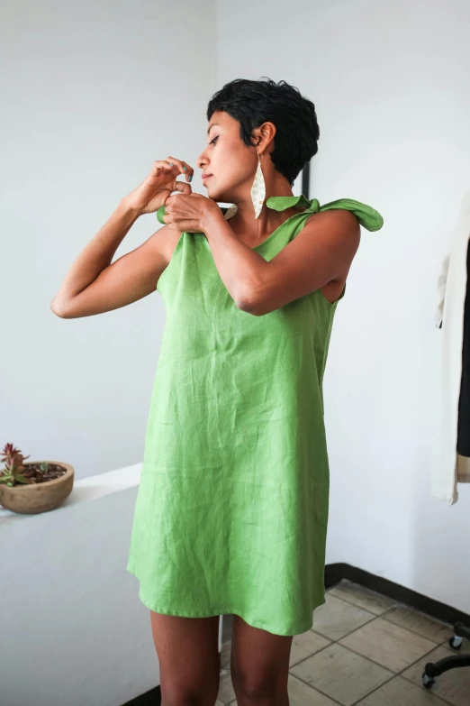 a woman in a green dress brushing her teeth, inspired by Eva Gonzalès, unsplash, happening, linen, holding maracas, green halter top, tunic