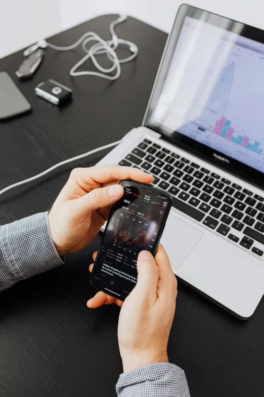 a person sitting at a desk using a cell phone, trending on pexels, pixel art, with a black background, charts, laptop, flatlay