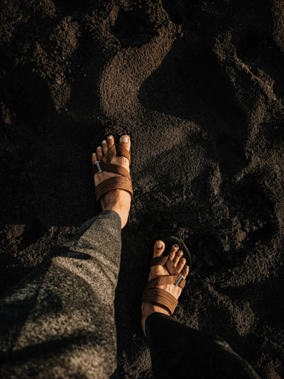 view of person wearing sandals standing on the sand