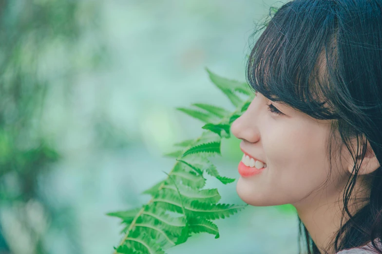 a close up of a person holding a plant, inspired by Kim Jeong-hui, pexels contest winner, side portrait of cute girl, profile image, smiling :: attractive, fern