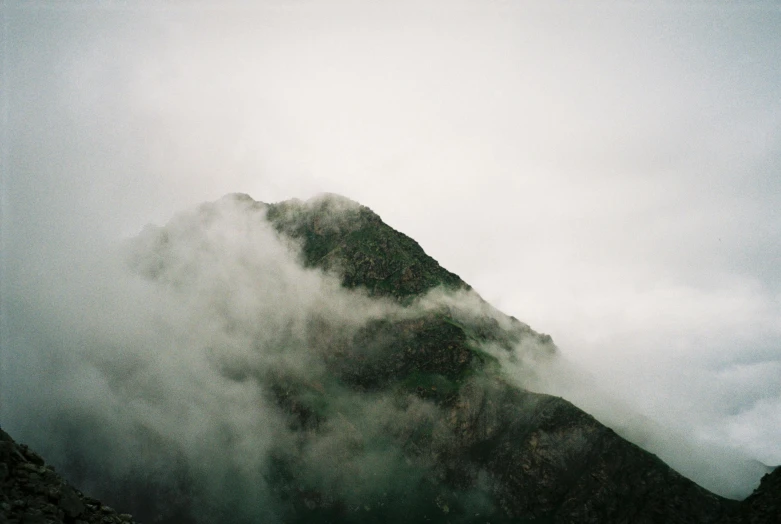 a mountain with clouds rolling in the sky