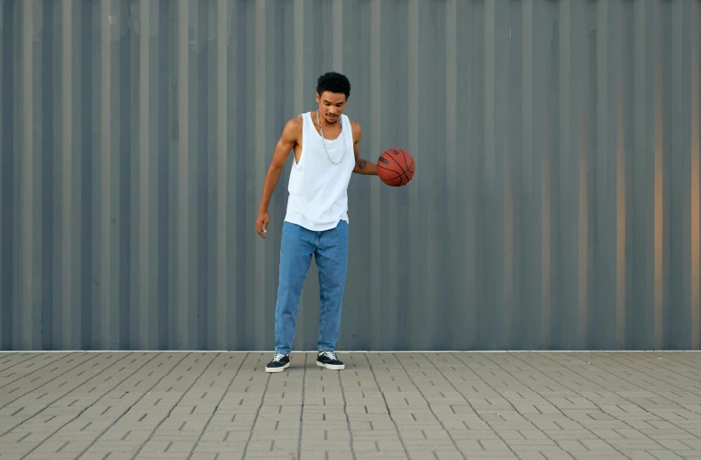 a young man holding a ball while standing next to a wall