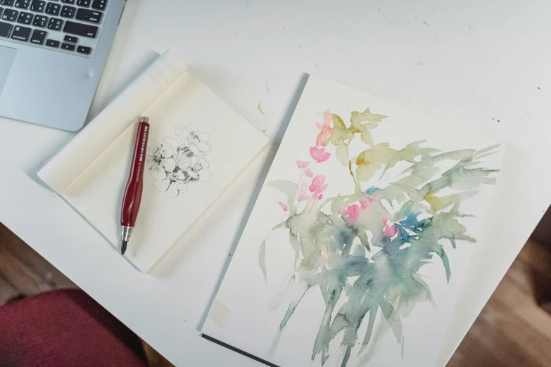 a laptop computer sitting on top of a white desk, a watercolor painting, inspired by Hasegawa Tōhaku, unsplash, study of a flower fairy, pencil and watercolour, viridian and venetian red, in a workshop